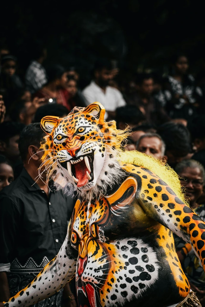 A person with tiger body paint and a mask in a crowd